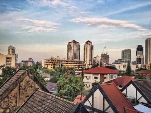 Roofs of houses on the background of new buildings and cloudy sky in Bangok