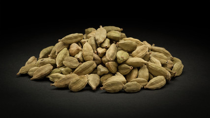 Pile of Organic Green or True cardamom (Elettaria cardamomum) on dark background.