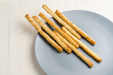 rustic breadsticks in a dish on wood table, close up, background