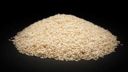 Pile of Organic Sesame white (Sesamum indicum) on dark background.