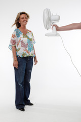Woman is cooled down by a handheld fan (against white studio back ground)