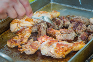 Mixed meat, chicken pieces and small kebabs, grilling and checking readyness.