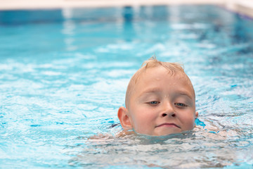 Fototapeta na wymiar A cute blond boy learning to swim