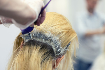 A hairdresser bleaching hair for a blonde female client