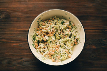 Salad with chickpeas in a bowl on a wooden table, top view