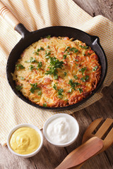 Rustic Potato pancakes with herbs close-up in a frying pan. vertical

