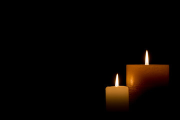 Two burning candles isolated on black background.