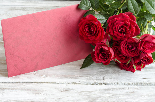 Bouquet of red roses with red wooden plank on table