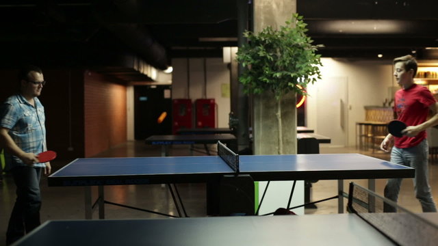Two male friends playing a game of ping pong