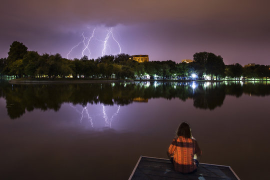 Man meditating in lotus position near a lake with thunderlight i