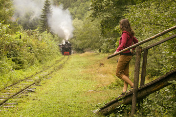 Fototapeta na wymiar Woman waiting a vintage old train in forest