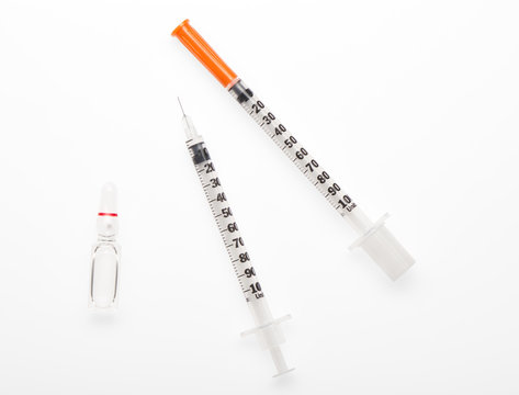 Plastic syringe with needle closed by protective cap, plastic syringe with open needle and transparent white glass ampoule with a drug isolated on white background. Clipping path included.