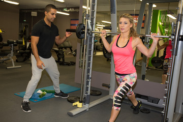 Woman exercise on shoulder press machine with personal trainer