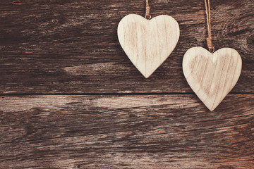 Fototapeta premium Two wooden hearts on wooden background. Copy space, soft focus, toned, vintage style