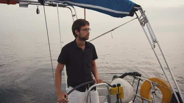 Young man is driving a sailing boat in the sea. Shot on RED Cinema Camera.