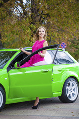 Portrait of a beautiful blonde woman and green sports car