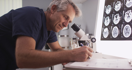 Middle aged male radiologist looking through microscope