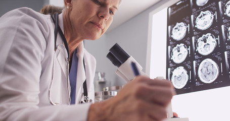 Middle aged female radiologist looking through microscope