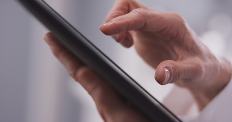 Elderly woman's hand typing on a tablet