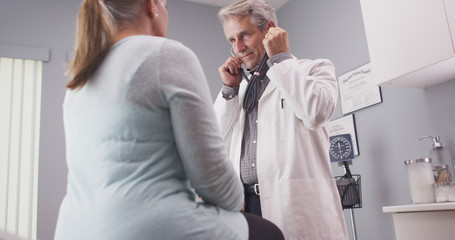 Obraz premium Male senior doctor listening to patient vitals with stethoscope