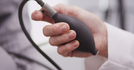 Close-up of nurse's hand pumping blood pressure monitor