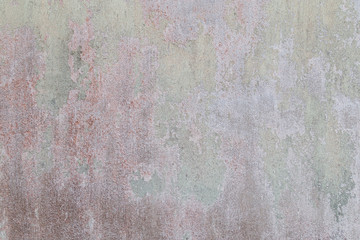 Weathered and old concrete wall with red paint peeled off.