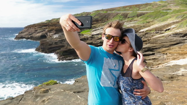 Couple tourists taking self portrait with camera phone on Hawaii, Oahu.