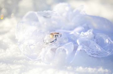 Обручальные кольца на кружевной подушечке на снегу