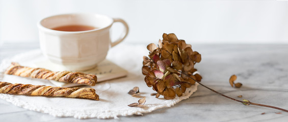 Cup of tea and cinnamon twist cookies with dried hydrangea flower 