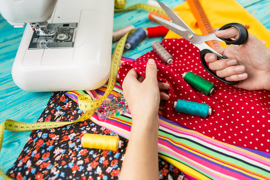 Hands mistress seamstress made a beautiful bright fashionable clothes. The crosslinking parts of the pattern. Work place. Top view. Light Textile industry creative moments