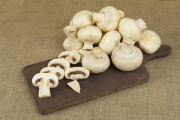 Raw mushrooms on a cutting board. Preparation of Champignons in the kitchen. 
