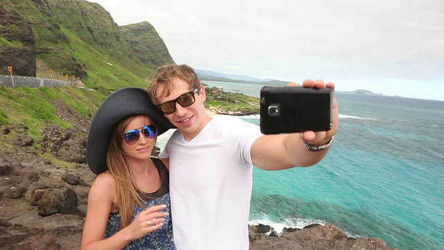 Couple tourists taking self portrait with camera phone on Hawaii, Oahu, Makapuu