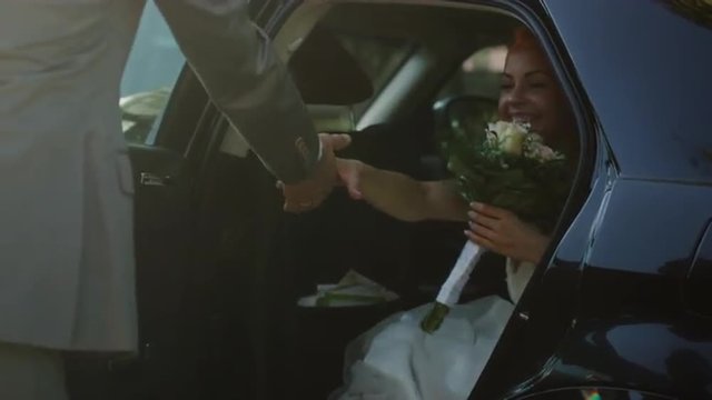 Groom opens and holds the car door for the beautiful young bride. Shot on RED Cinema Camera.