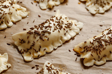 Raw pasties with puff pastry stuffed with cabbage and mushrooms sprinkled with caraway seeds before baking