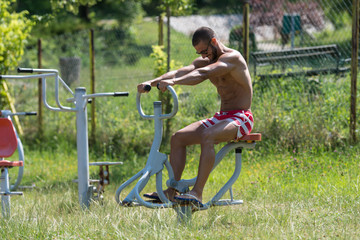 Fototapeta na wymiar Muscular Man Training On The Playground In Park