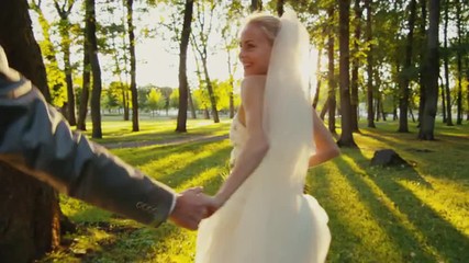 Smiling bride holds groom by the hand and runs in a park - Powered by Adobe