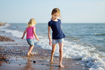 Two little sisters having fun on a sandy beach