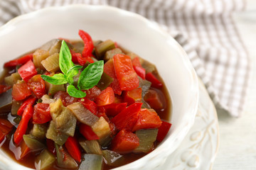 Ratatouille in bowl, on wooden table background