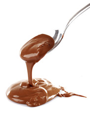 Melted milky brown chocolate pouring from a spoon, isolated on white
