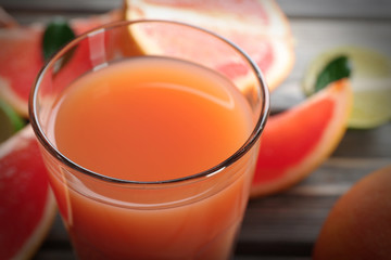 Glass of grapefruit juice and fresh fruits on wooden background