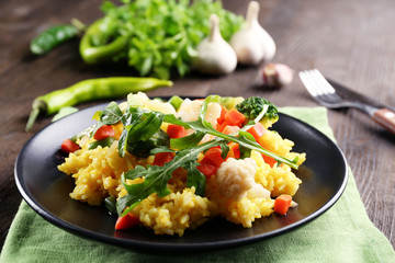 Black plate with vegetable risotto on served wooden table