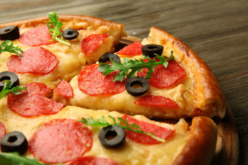 Hot tasty pizza with salami and olives on wooden background