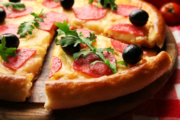 Delicious tasty pizza with salami and olives on wooden background, close up
