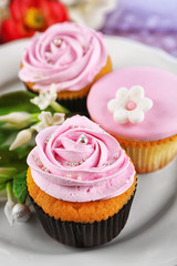 Tasty cupcakes on plate, on color wooden background