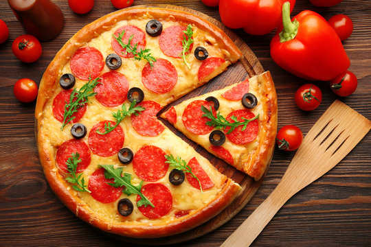 Hot tasty pizza with salami and olives on wooden background, close up