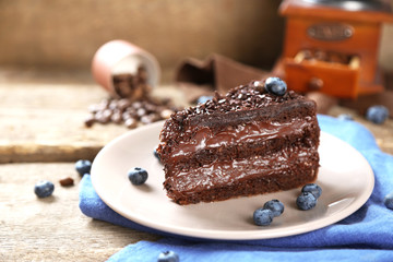 Chocolate cake with chocolate cream and fresh blueberries on plate, on wooden background