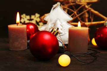 Burning candles with Christmas accessories on wooden background