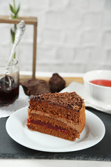 Sliced chocolate cake on wooden table, on light background