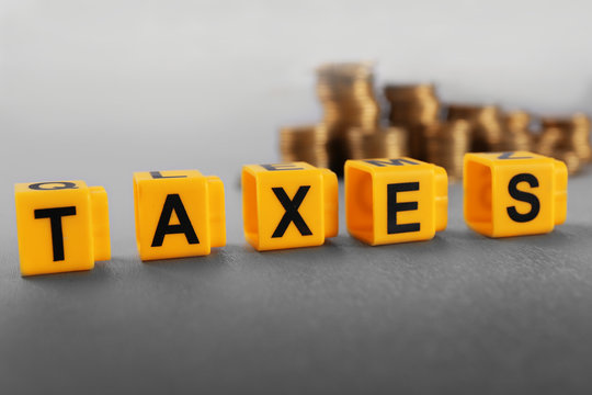 Alphabet TAXES and golden coins on table