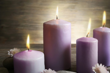 Spa set with candles, pebbles and flowers on wooden background, close up